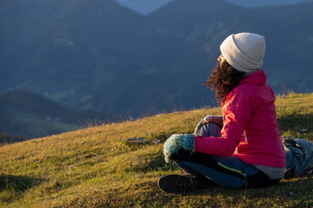 istock Brunette sitting on grass slope and meditating at sunset 1405908129
