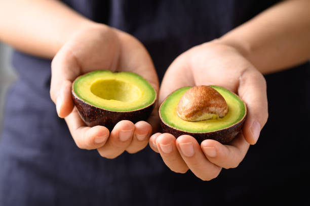 Ripe avocado fruit holding by hand ready to eating stock photo