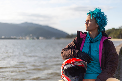 Blue haired latin woman looking at horizon with helmet