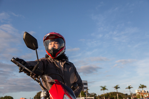 Latin woman on motorbike with blue sky in background