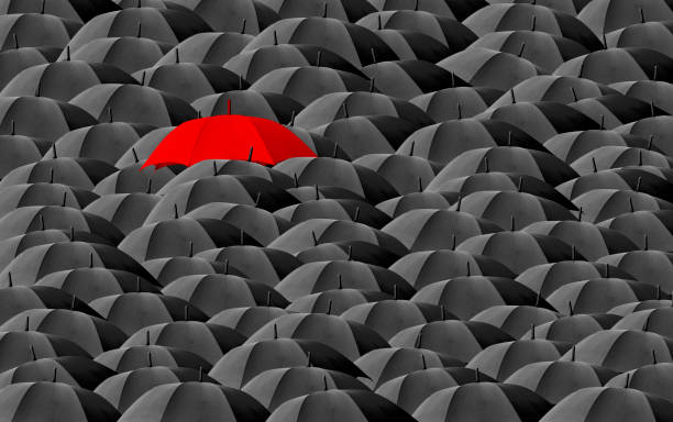 Red umbrella surrounded by many black umbrellas