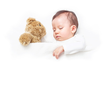Asian Baby sleeping with her teddy bear on the bed