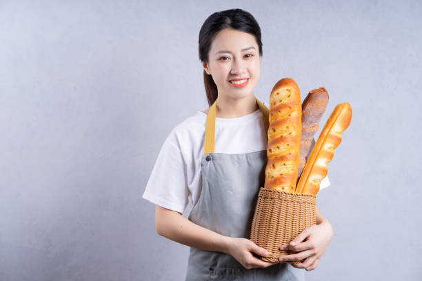 istock Young Asian woman holding bread on background 1405923800