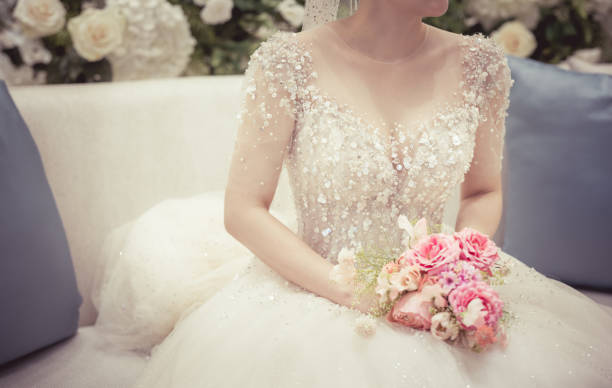 Bride sitting and holding the wedding bouquet, Detail image cut.