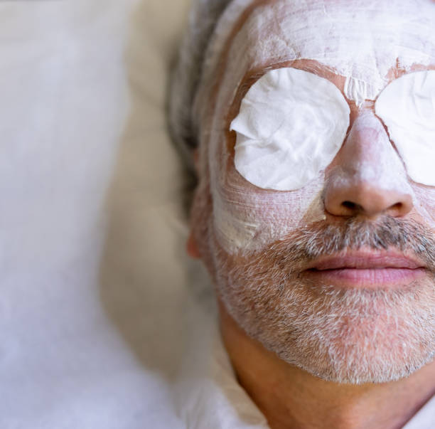 mężczyzna w spa dostaje odmładzającą maseczkę na twarz - peeling beauty treatment human face beautician zdjęcia i obrazy z banku zdjęć