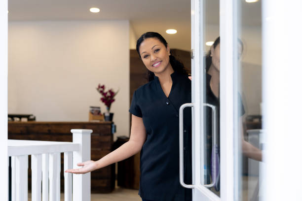 esthéticienne heureuse accueillant les clients dans un spa à la porte - esthéticienne photos et images de collection