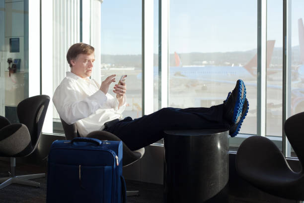istock Businessman relaxing in airport terminal while using his cellphone 1405937673
