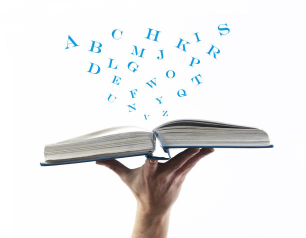 istock Hand holding opened book with flying, scattered letters  on white background. Education concept. 1405941020