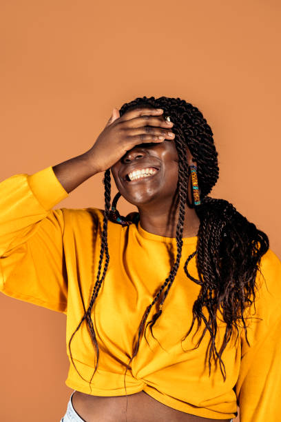 Happy African Woman Portrait Stock photo of beautiful black woman smiling and having fun in studio shot. hair covering eyes stock pictures, royalty-free photos & images