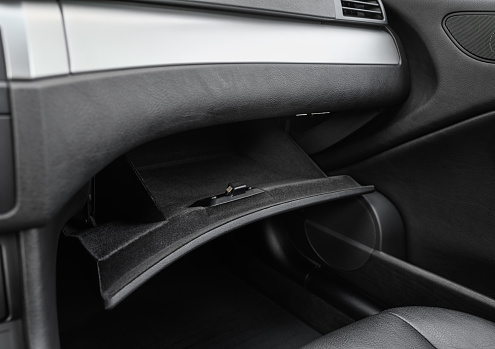 An empty and clean glovebox (glove compartment) inside a modern car, viewed from the driver side.