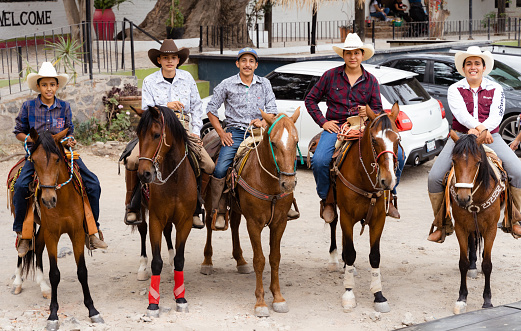 Chapala, Jalisco / Mexico - May 10, 2021: Five proud Mexican Charros posing on horses with a smile. Traditional cowboys from Mexico standing in a row