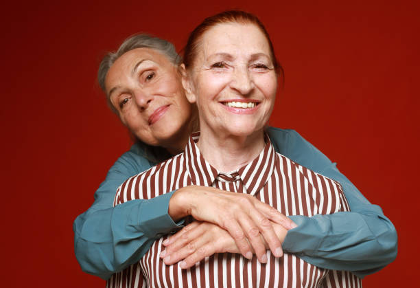istock Two pretty older women hugging on red background. Lifestyle concept. 1405947788