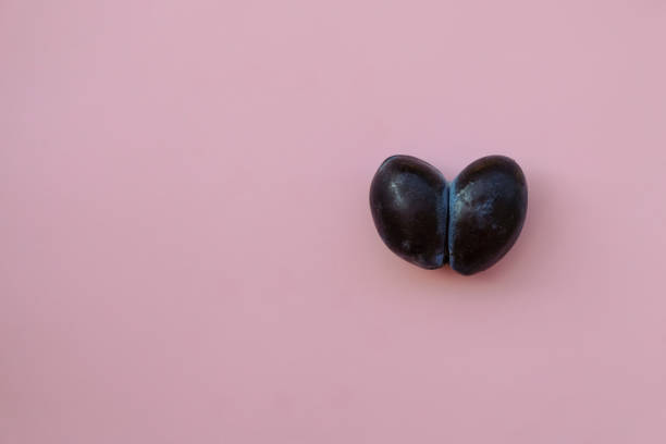 Two heart-shaped plums. Amaranth Pink Color background. Copy space.