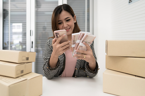 Young Asian Woman sit working from home, selling online in small business.