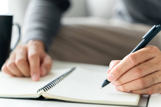 istock left handed man writes in a notebook on the table 1405954415