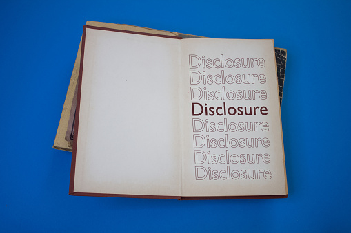 Disclosure word in opened book with vintage, natural patterns old antique paper design.
