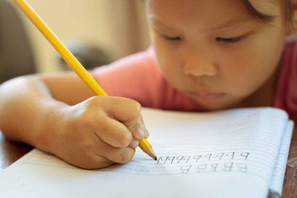 istock A kindergarten student holding a pencil, learning how to write the alphabets. children education 1405955861