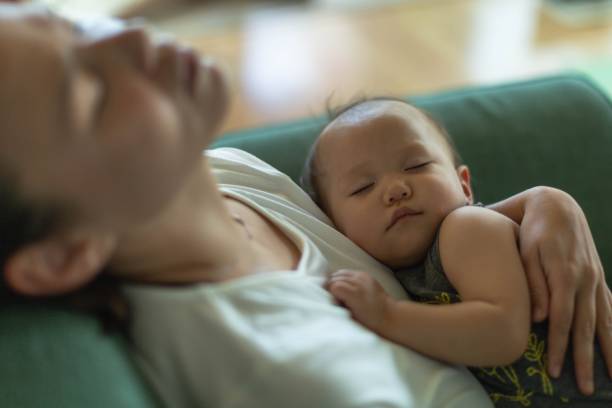 una madre stanca che dorme con il suo bambino. depressione postpartum. - asian ethnicity baby mother family foto e immagini stock