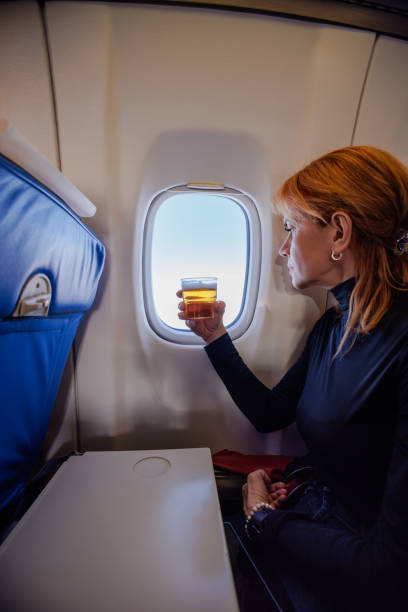 istock Woman having a drink on the flight and looking through window 1405959598