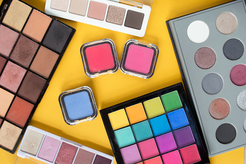 Colorful and nude eyeshadow palettes on yellow background