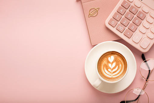 Calculator, a cup of coffee with a beautiful pattern and a notepad on a pink background. Place for text. High quality photo