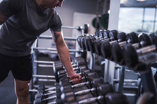Close-up of man's hands taking dumbbell