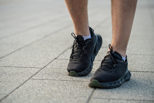 Close-up outdoors shot of adult male legs in black running sneakers
