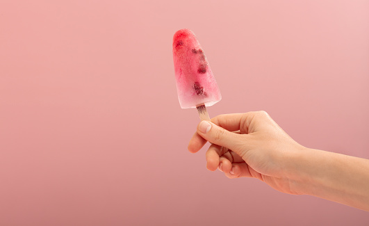 Woman hand holding an ice cream cone on a pink background. . High quality photo