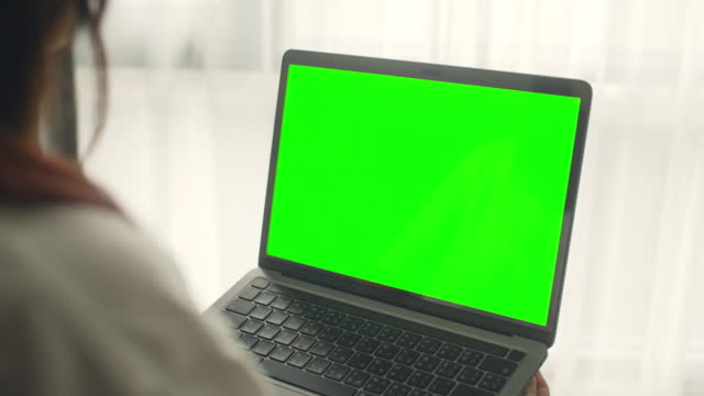 Woman using chroma key green screen laptop at home