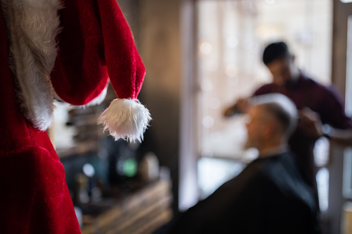 Male Caucasian barber, triming the Santa Claus beard, at the barber shop