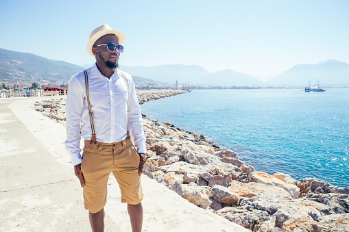 handsome african american person casual fashion look outfit in straw hat,white shirt walking by Tyrkey coast
