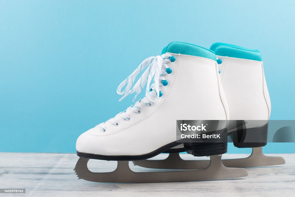 Pair of ice skaters in front of a blue background, winter sport equipment Figure Skating Stock Photo