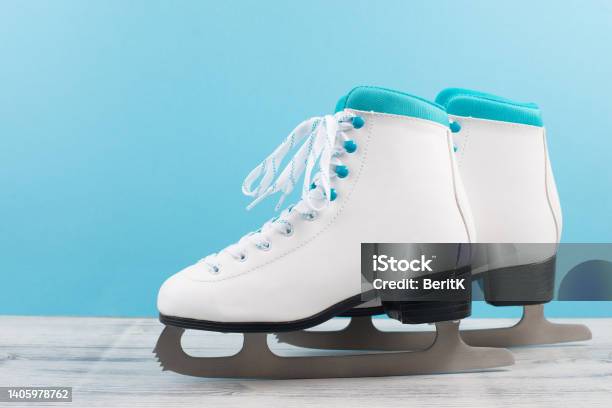 Pair Of Ice Skaters In Front Of A Blue Background Winter Sport Equipment Stock Photo - Download Image Now