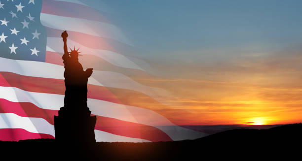 statua wolności z dużą amerykańską flagą i zachodem słońca na tle. - crown liberty statue zdjęcia i obrazy z banku zdjęć