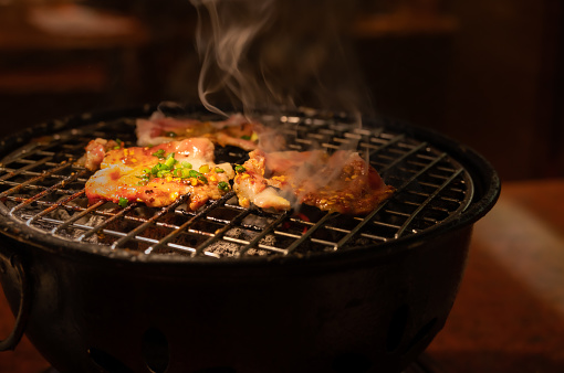 Sizzling pork slices grill on charcoal, Korean or Japanese BBQ style cuisine.