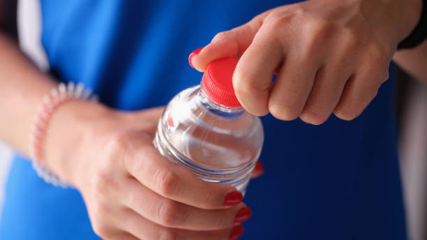 istock Woman opens plastic red cap of water bottle 1405980473