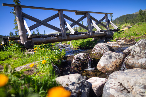 Wooden bridge over stream  in mountains of Ergaki natural reserve, Russia.