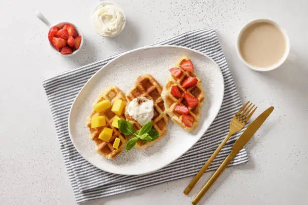 Photo of Tasty breakfast with croffles and morning coffee, strawberries. Croissant as waffle.