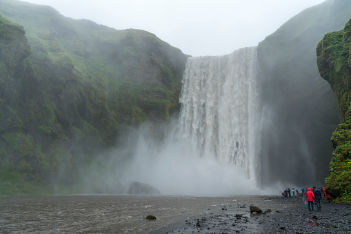 Small group of unrecognizable person in distance at Skogafoss waterfall in Iceland