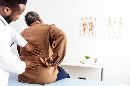 Male doctor hands doing physical therapy By extending the back of a male patient