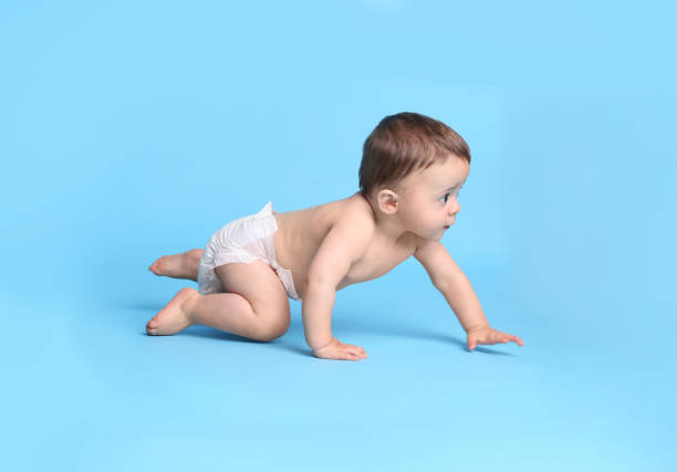 istock Cute baby in dry soft diaper crawling on light blue background 1405986934
