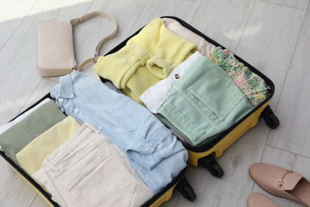 istock Open suitcase packed for trip, handbag and shoes on floor 1405987830