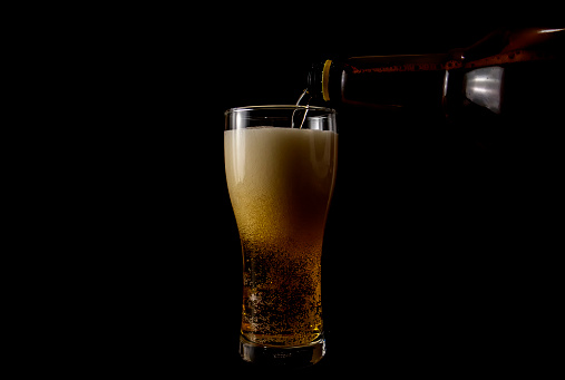 Pouring beer into a glass on a black background.