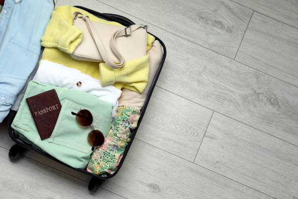 istock Open suitcase with clothes and accessories on floor, top view. Space for text 1405988108
