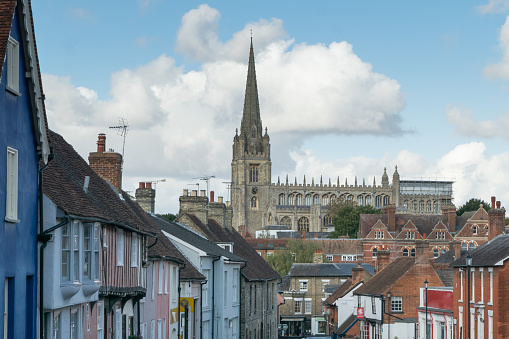 Facade of old colorful terraced cottage houses with Cathedral tower visible in Saffron Walden, England
