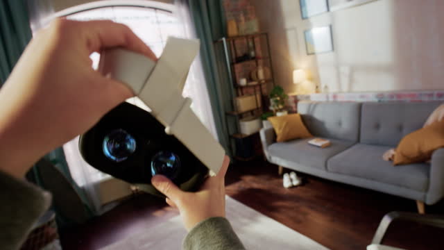 POV of a Person Picking Up and Putting On Virtual Reality Headset in Living Room at Home. Mock Up for Inserting Your Own VFX Virtual Reality 3D Universe, Digital Office Interface, Social Platform.