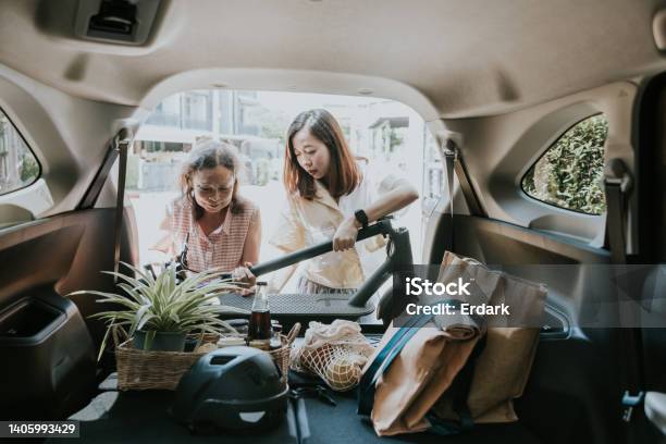 Asian Woman Folding Her Escooter And Carrying In He Car Trunk Stock Photo - Download Image Now