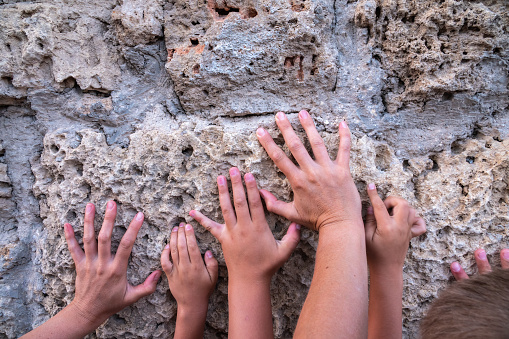 Hands of a woman and children on the background of an old wall. Hand on sandstone wall