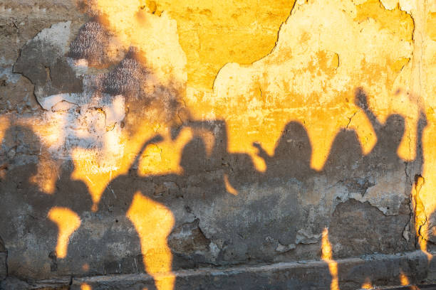 istock Shadows of dancing people on an old stone wall at sunset time. 1405993663