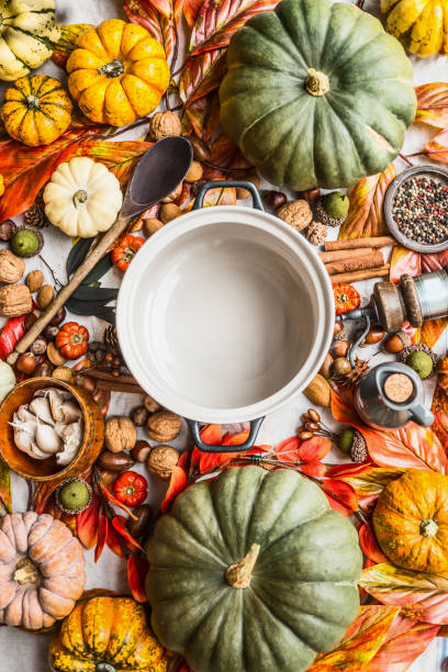 istock Empty coking pan with wooden spoon on table with many various colorful pumpkins and other autumn ingredients: nuts and spices. 1405994565